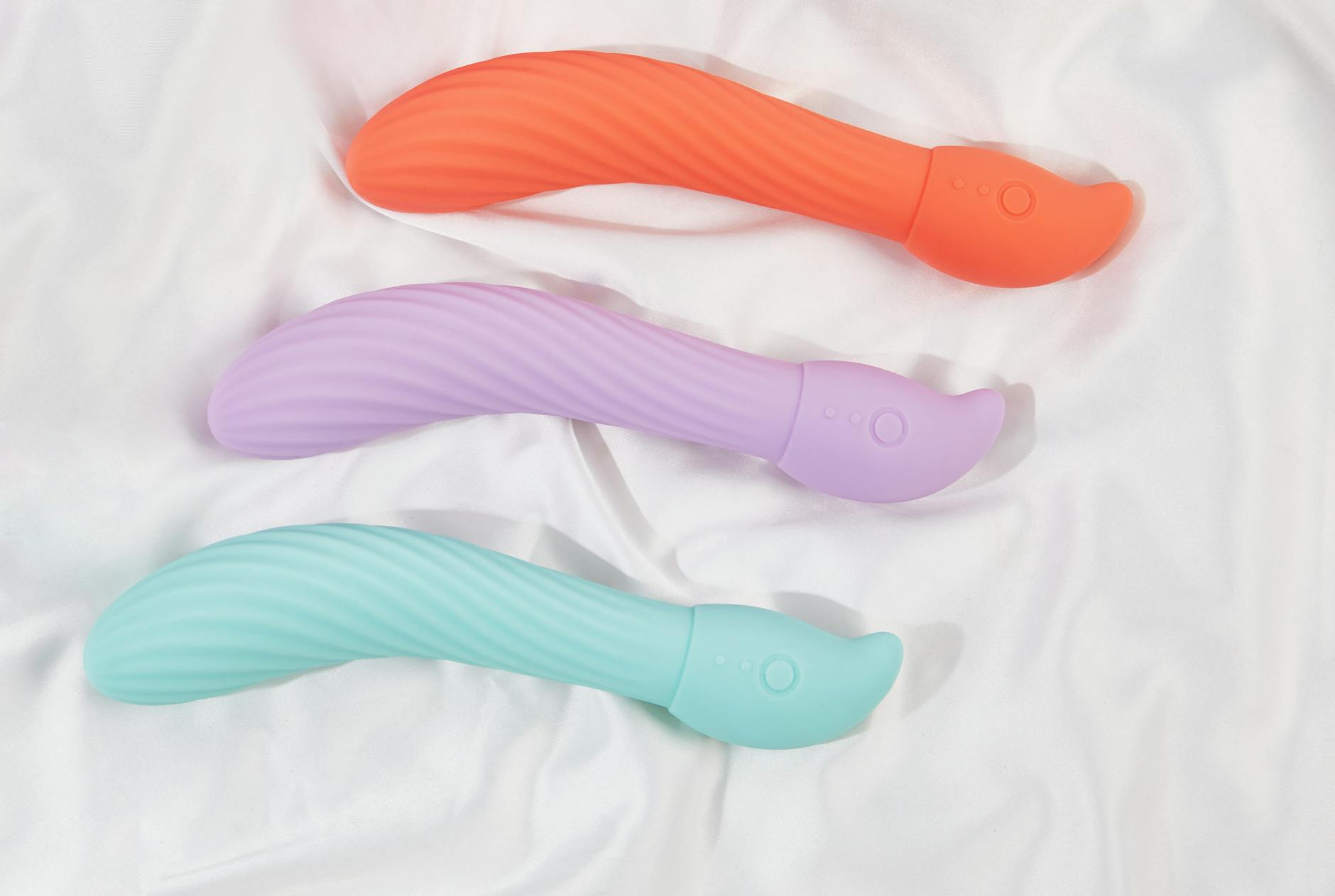 Three colorful clitoral vibrators arranged on white fabric, highlighting their smooth suction design.