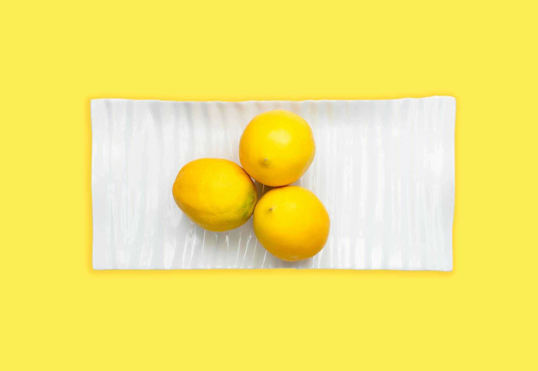 Vibrant lemons on a bright yellow background, symbolizing the fresh sensation of switching to lemon clitoral vibrators