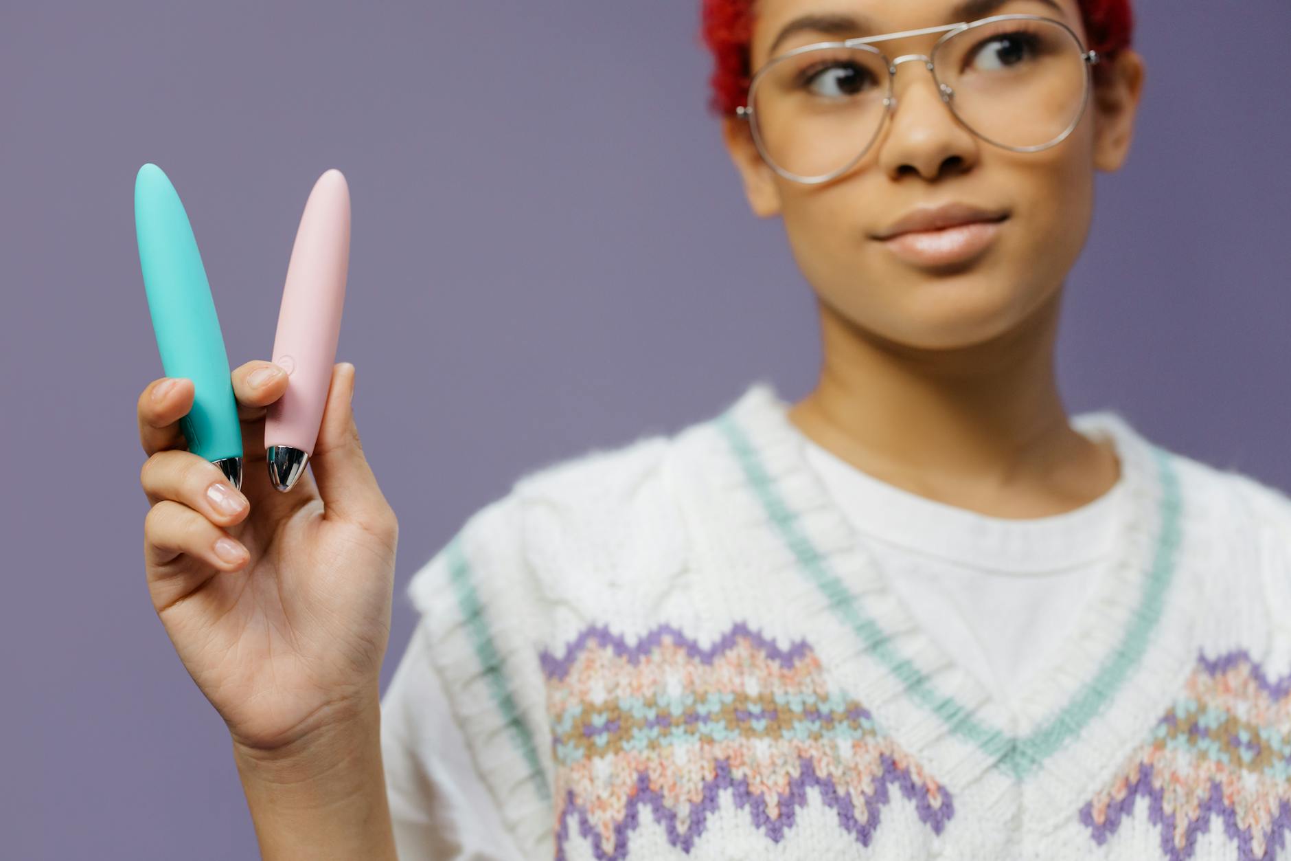 Two colorful vibrators held against a purple background, representing lemon sexual toys for pleasure restoration