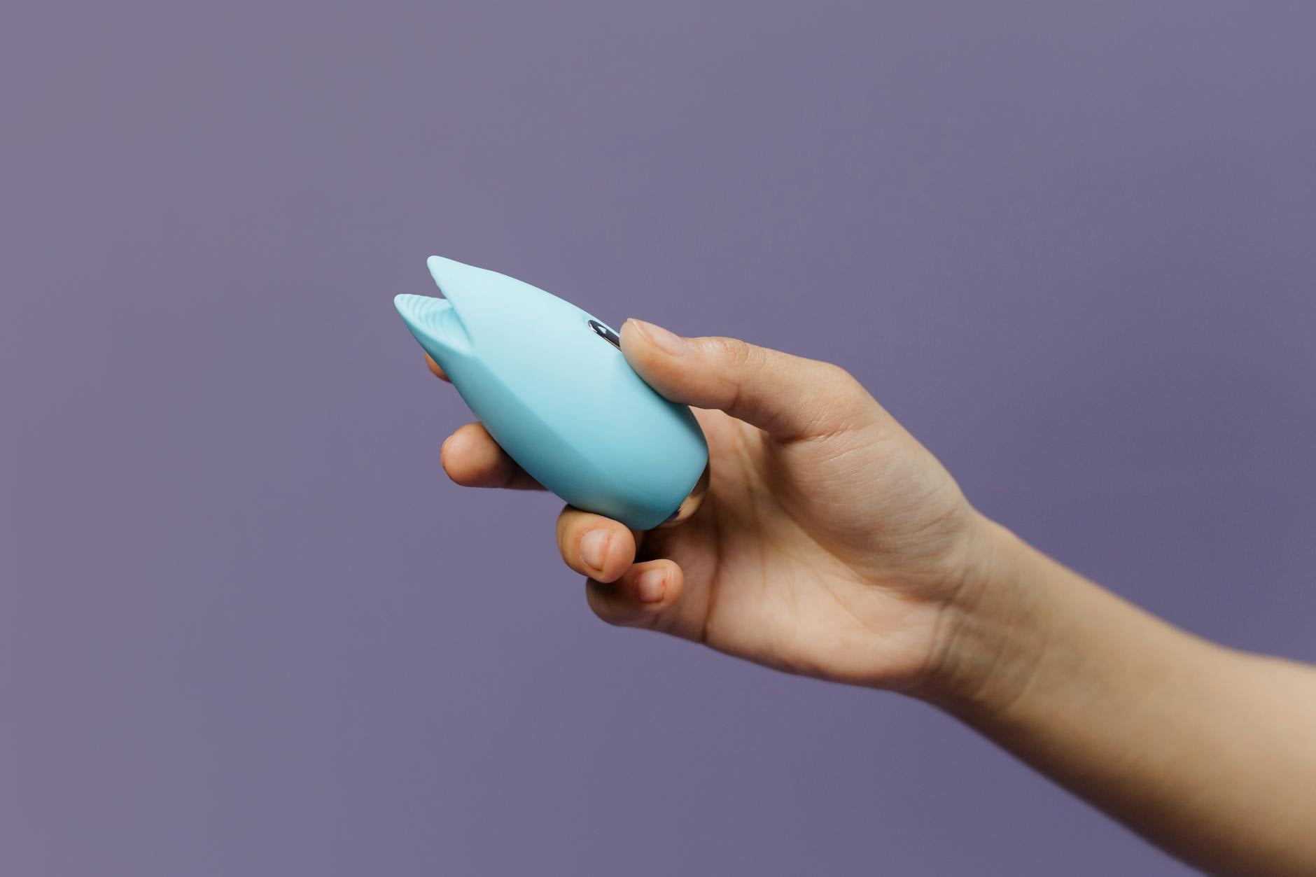 A vibrant blue silicone vibrator held against a purple background, symbolizing modern pleasure and sensual self-discovery