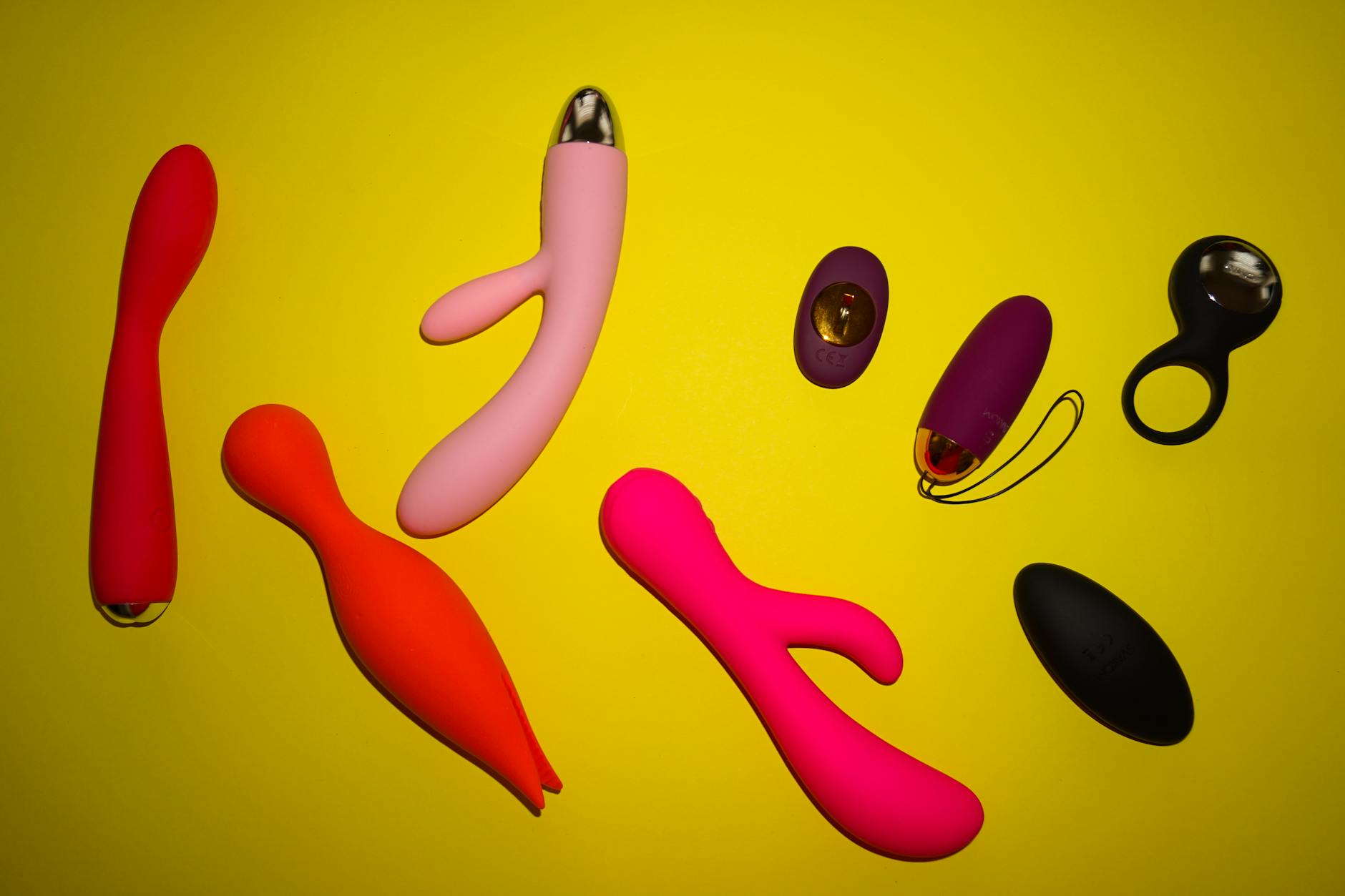 Colorful lemon vibrators and clitoral vibrators arranged on a bright yellow surface