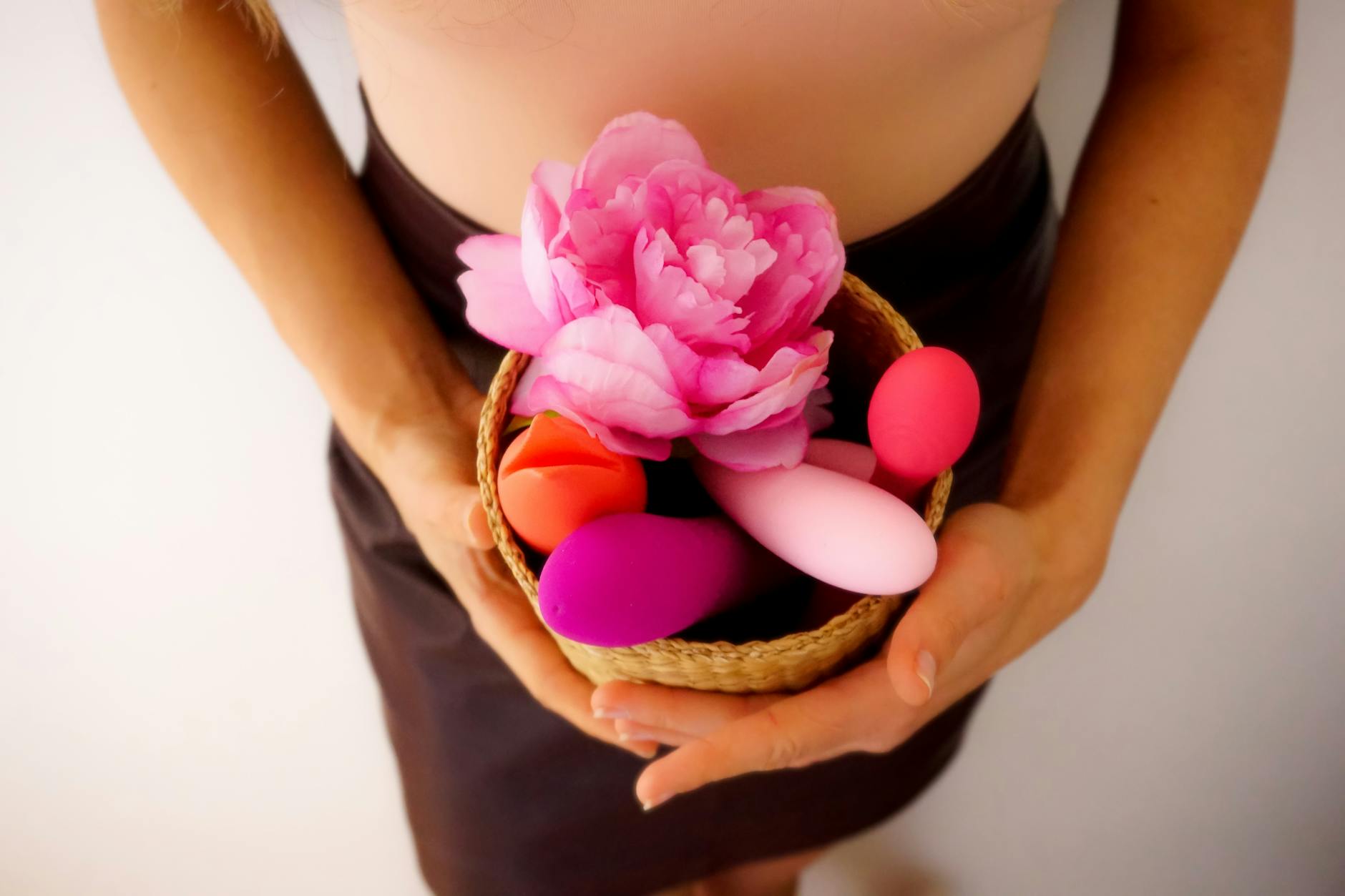 A colorful collection of lemon clitoral vibrators and wellness products arranged in a woven basket with fresh flowers